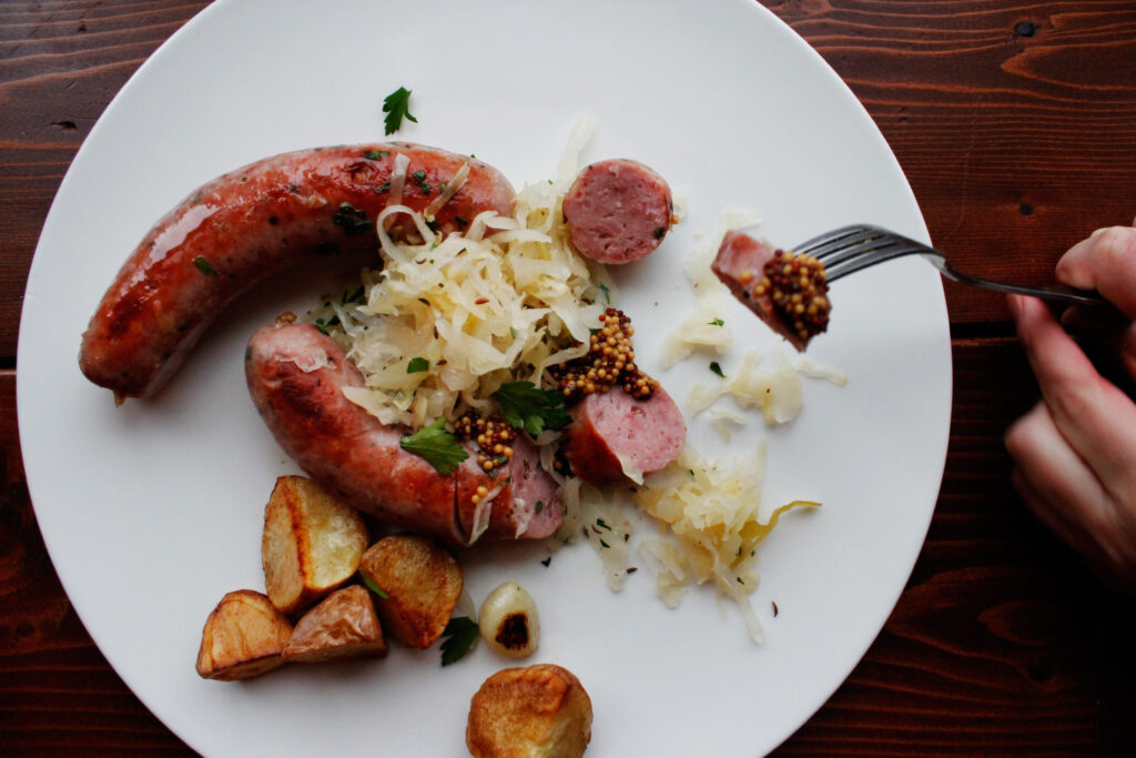 Two brats on a plate with kraut and potatoes