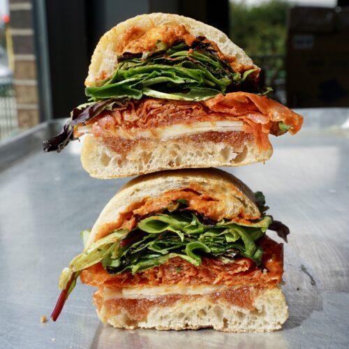 Sandwich on ciabatta with meat, cheese, greens