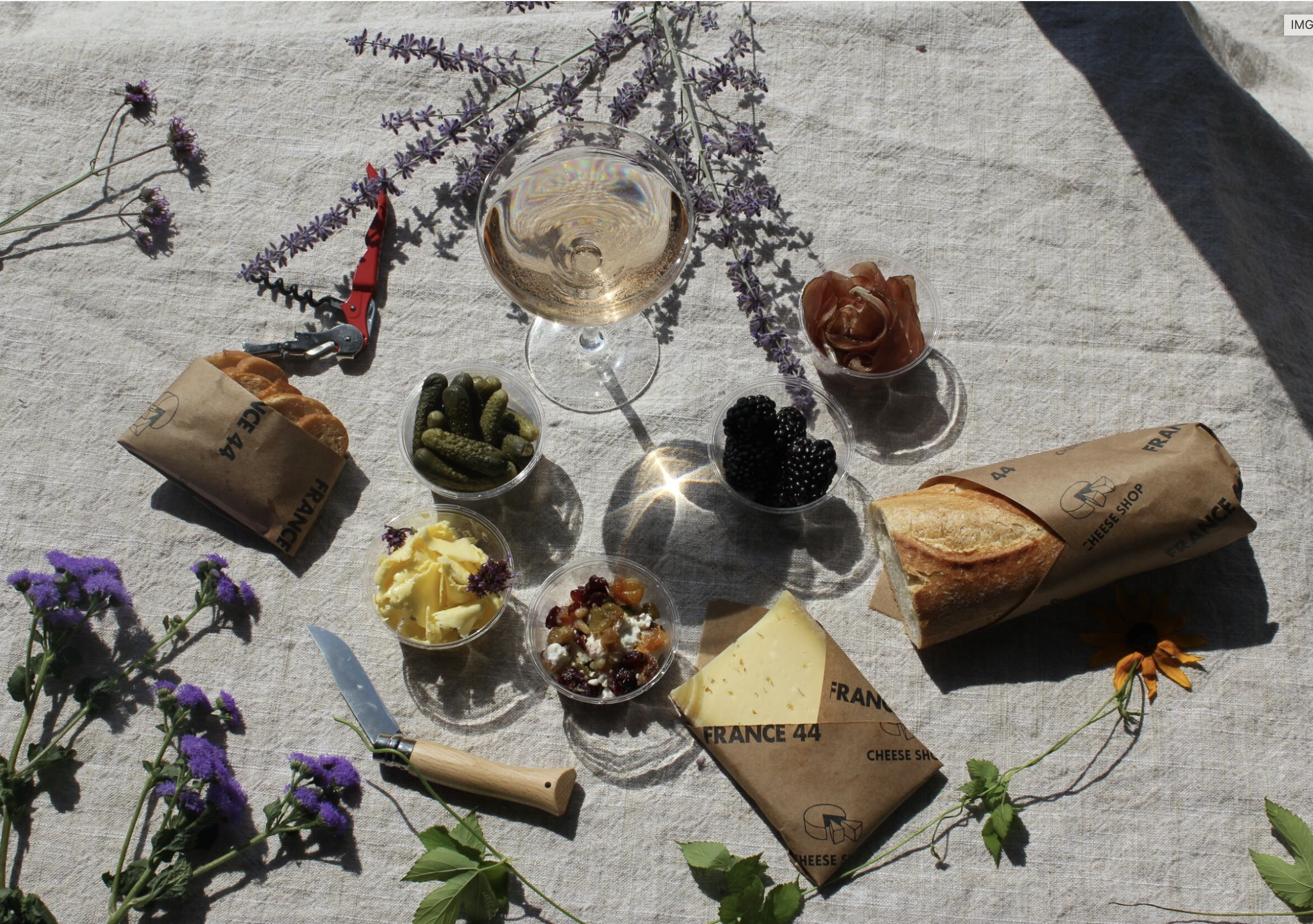 Birdeye view of picnic with baguette, cheese, drink