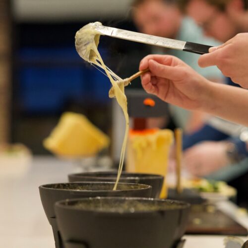 Hands spooning fondue onto a plate