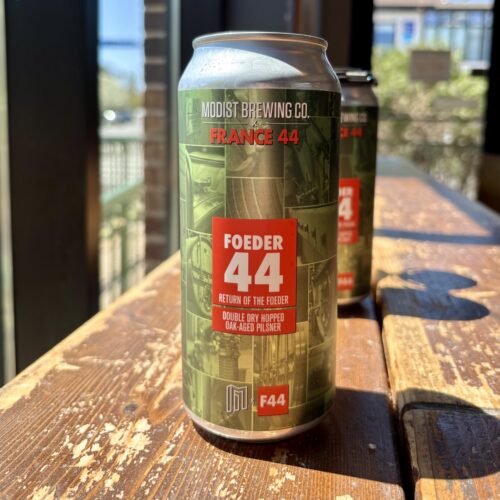 Green can of beer with F44 logo sitting on wooden table in front of a lot of sunny windows