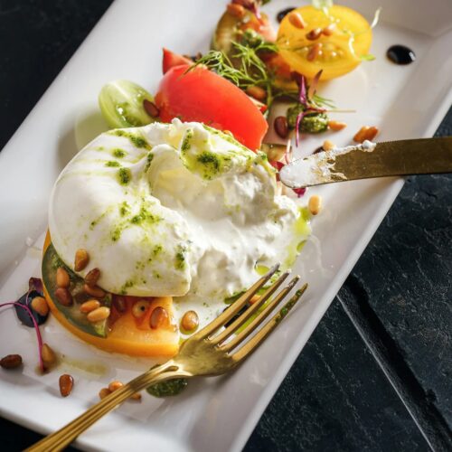 ball of buratta atop fresh tomatoes and pine nuts