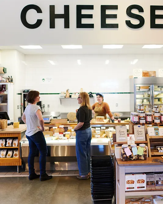 two community members talking at cheese counter