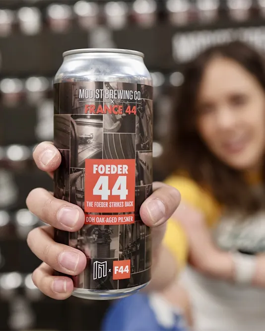 womans hand holding can of locally-brewed beer