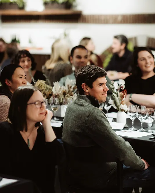 an audience smiling an sitting at a table