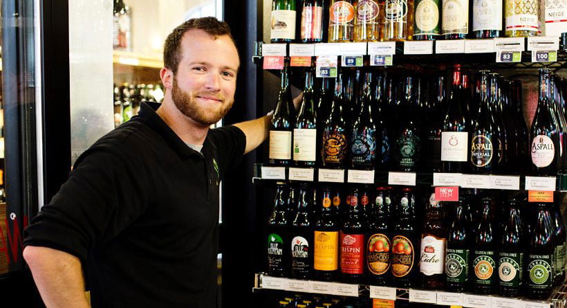 employee standing by shelf filled with cider wines