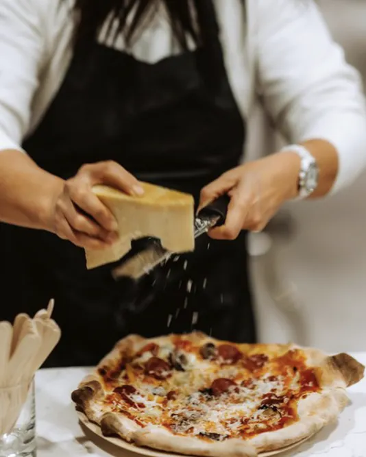cheese being put on pizza