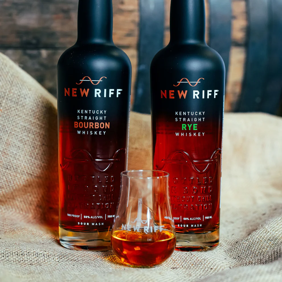 New Riff bottles beside a glass of bourbon