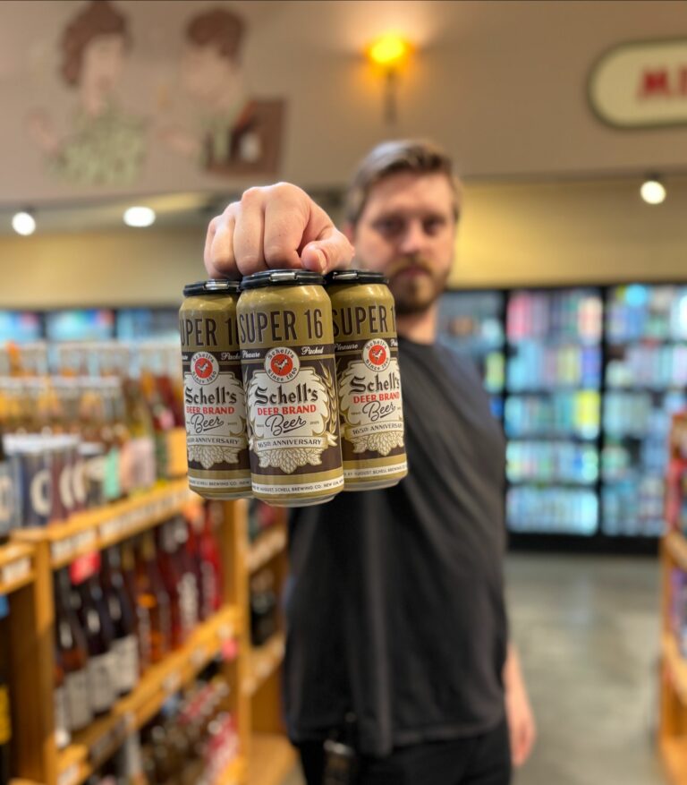Dylan holding up a 4 pack of Schell’s Deer Brand Lager