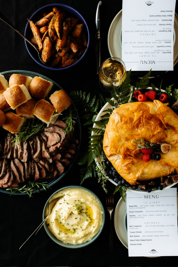 beef tenderloin, roasted carrots, mashed potatoes, and baked brie on the table
