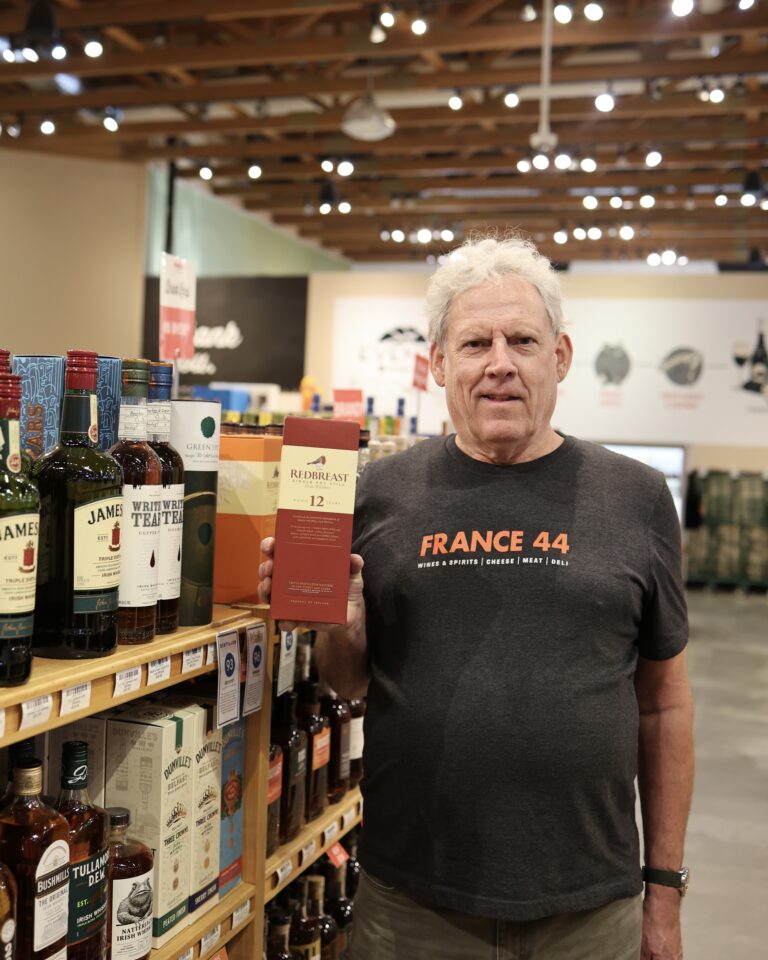 Jim holding up a box of Redbreast 12-year Irish Whiskey in the Whiskey aisle of France 44