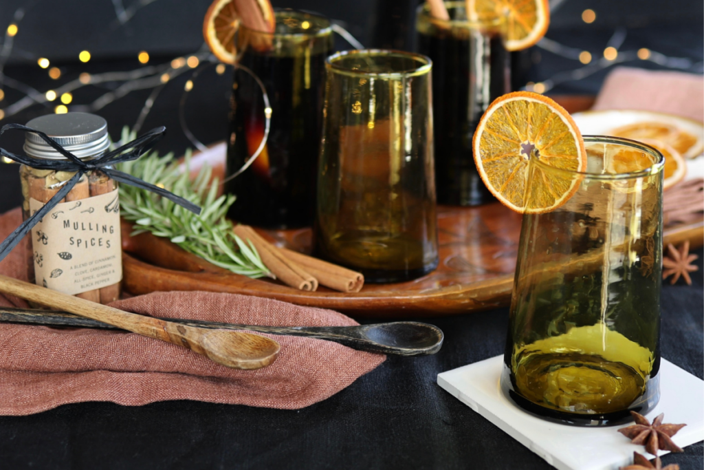 table filled with accessories including glassware, garnishes, napkins, mulling spices