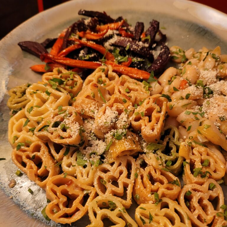 heart shaped colorful pasta on a plate with mixed vegetables