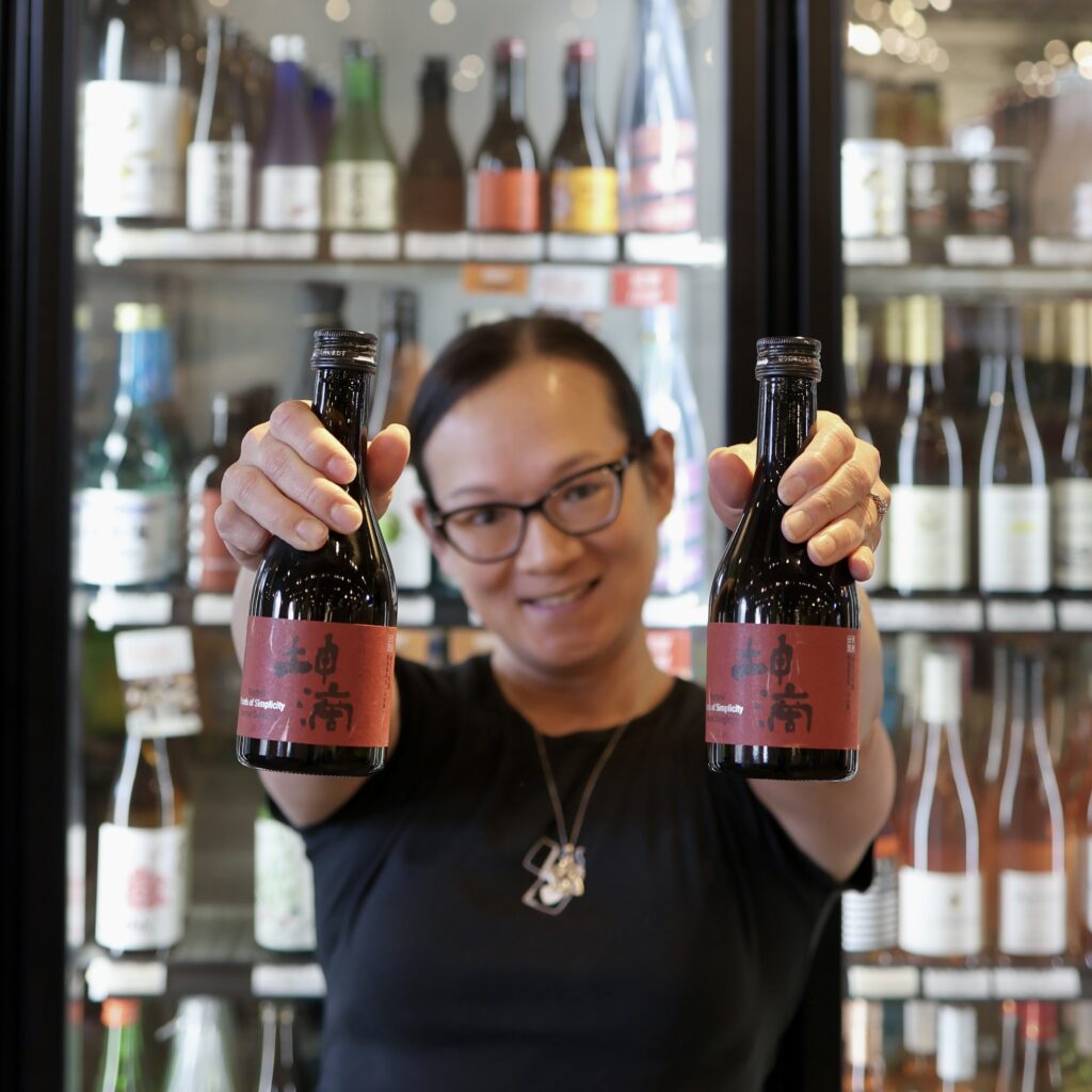 TK holding up two bottles of Konteki "Pearls of Simplicity" Junmai Daiginjo Sake in front of the Sake case