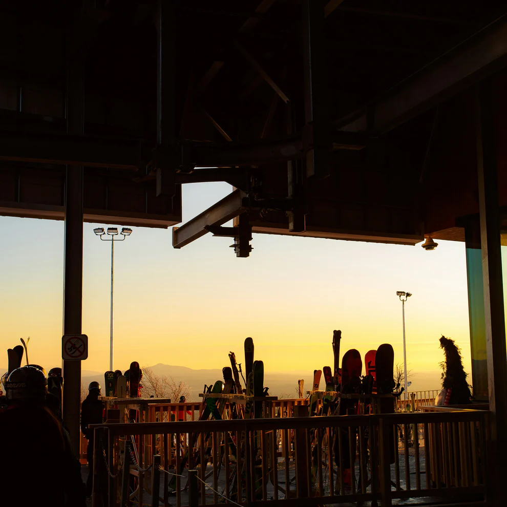 Sunset over a ski lodge balcony - silhouettes of skis & people outside