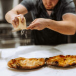 grating parmigiano regigano on a pizza