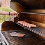 Someone checking the internal temp of brats on the grill