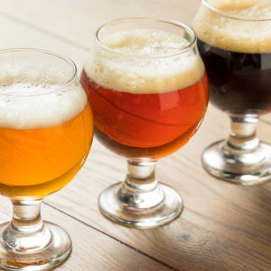 3 small glasses of beer on a wooden table