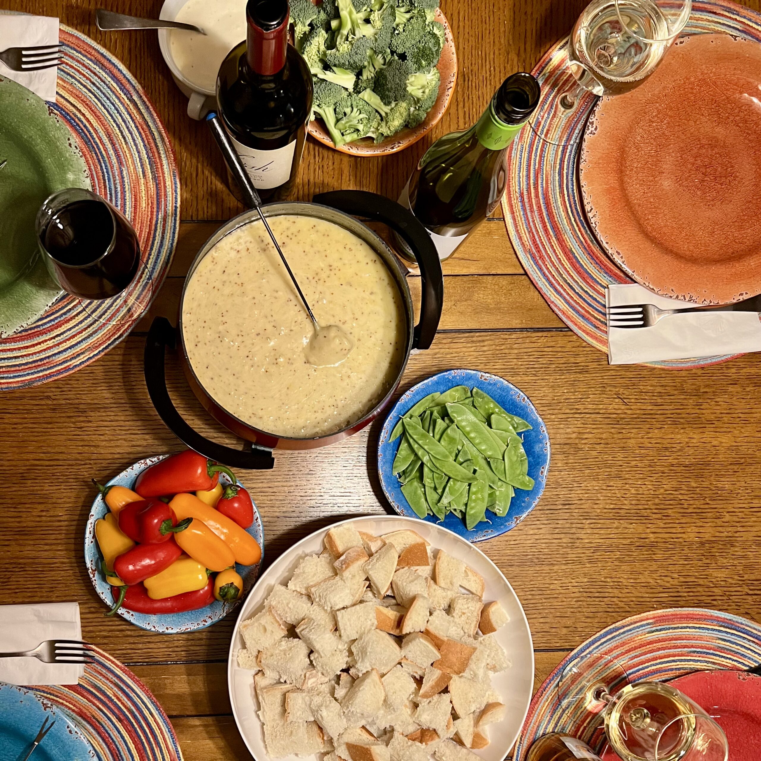 Table set with fondue, wine, and accoutrements