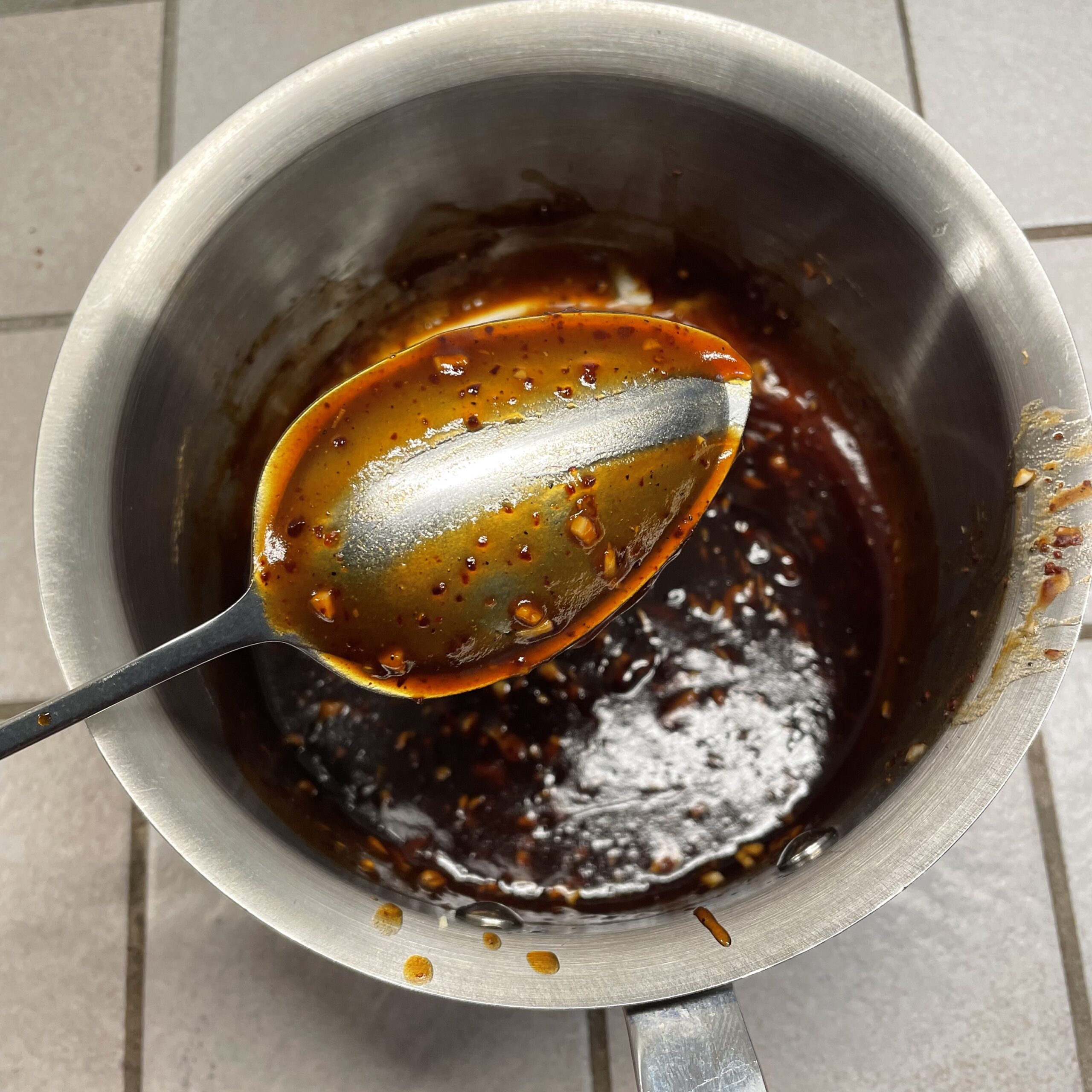 small stainless steel pot of dark brown glaze