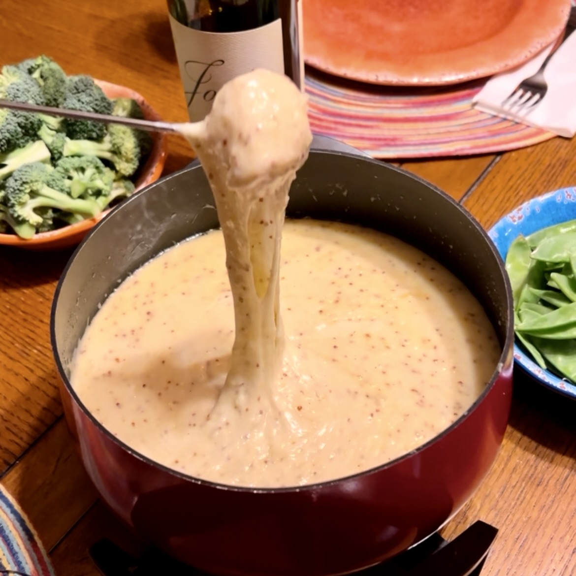 dipping a piece of bread into a pot of fondue