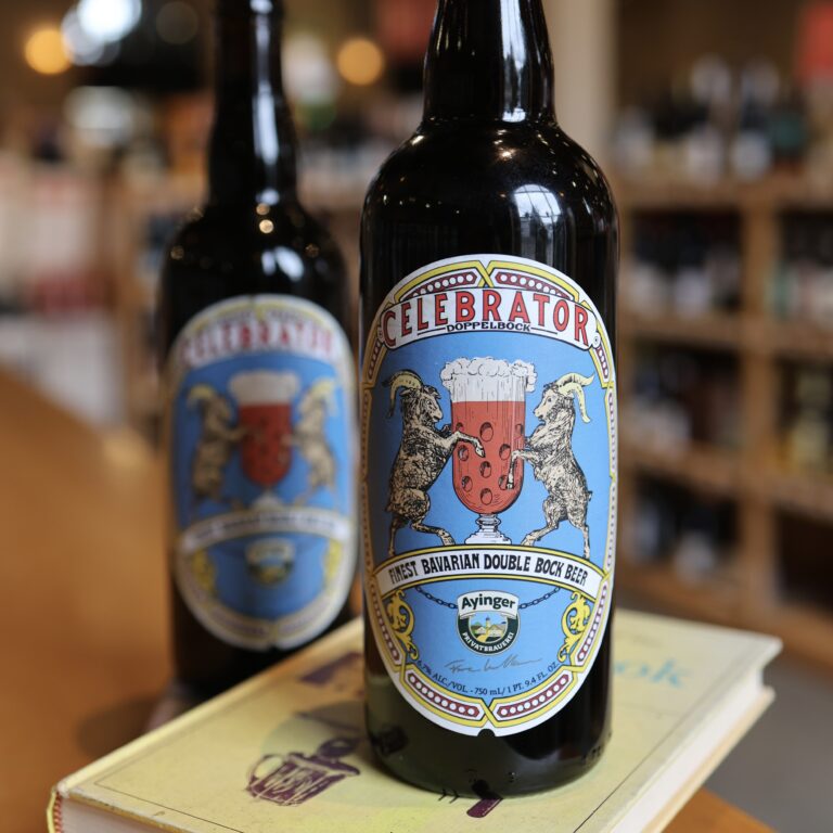 Two bottles of Ayinger Dopplebock sitting on a book in the liquor store