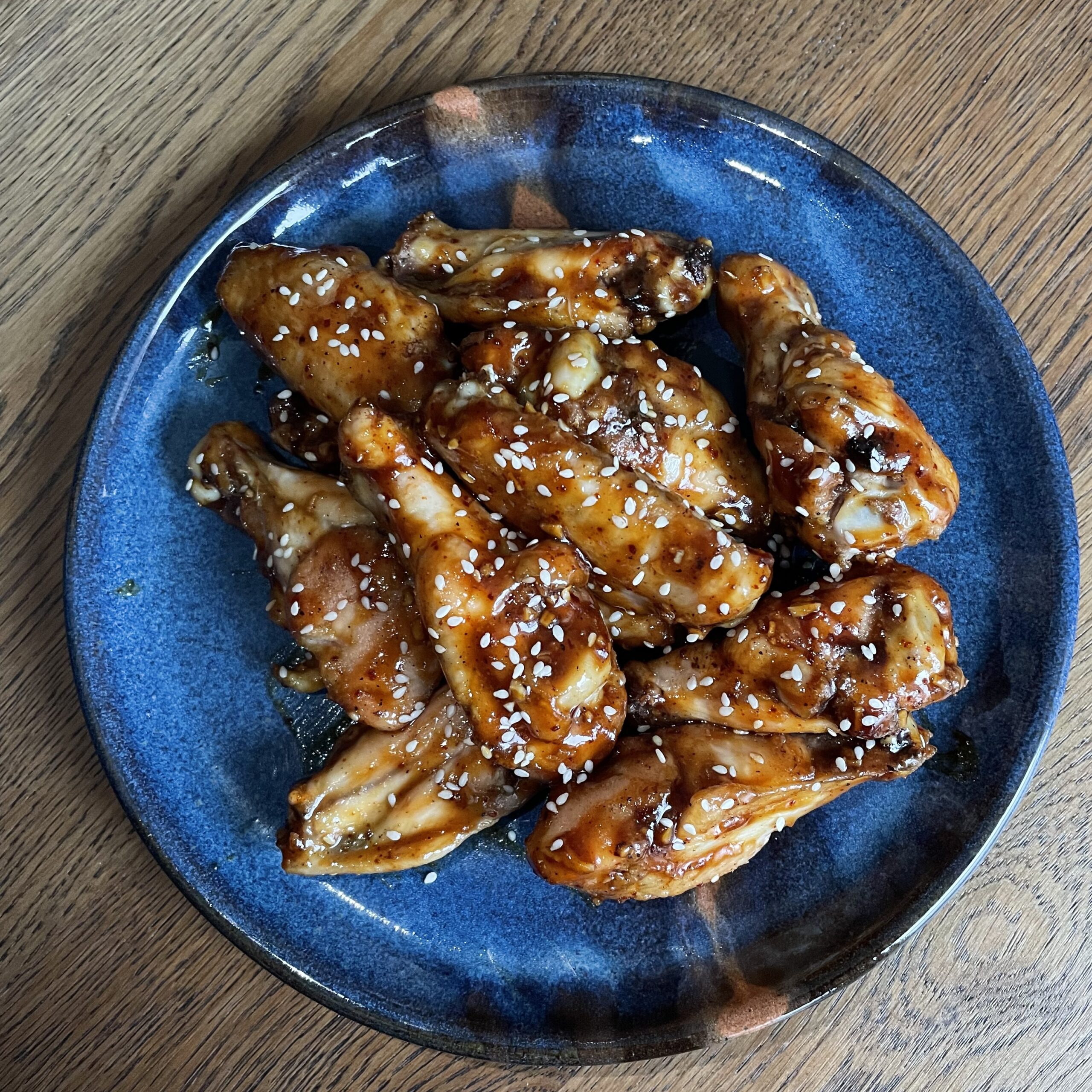 blue plate of glazed chicken wings on a wooden table