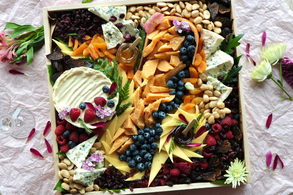 Cheese board on a pink background with flower pedals