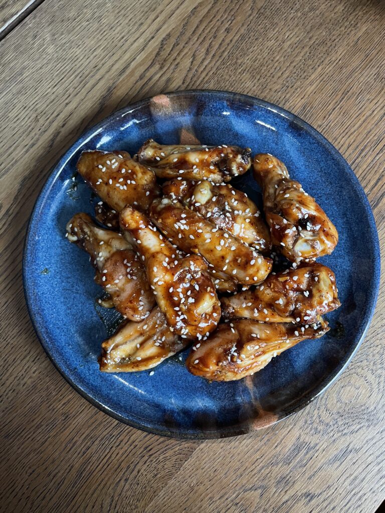 blue plate of glazed chicken wings on a wooden table