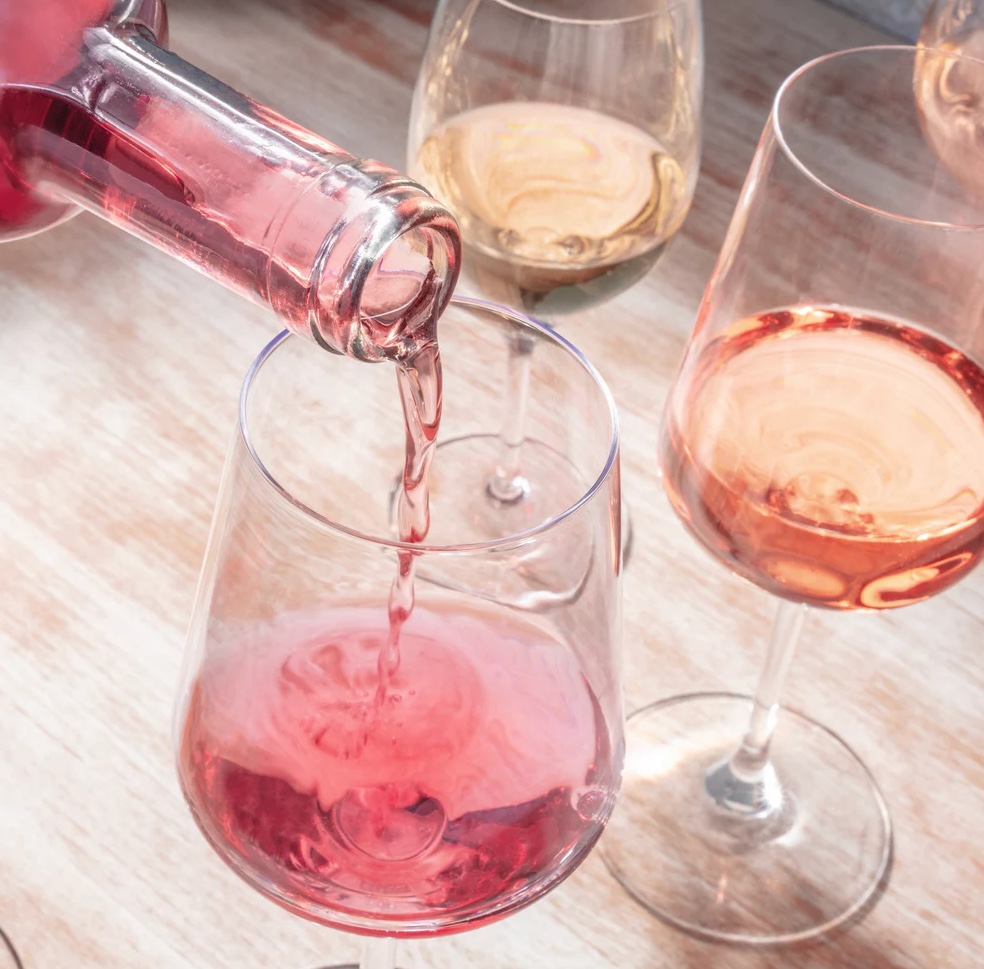 Pouring a glass of rose on a wooden table