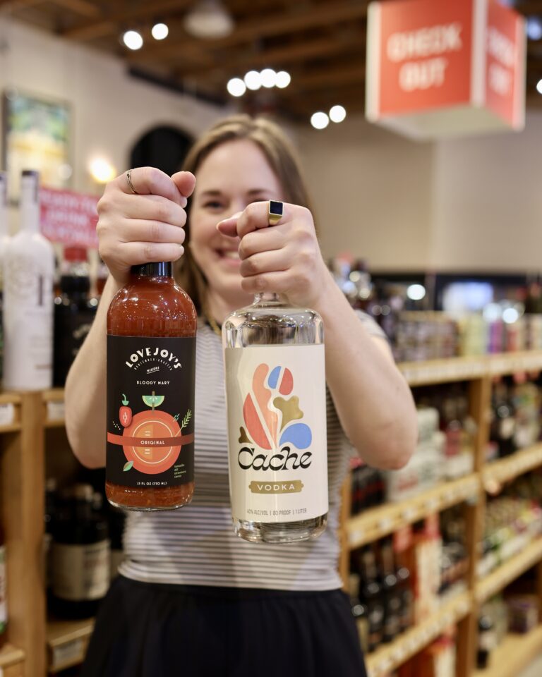 Sara holding up a bottle of Lovejoy Bloody Mary Mix and a bottle of Vodka