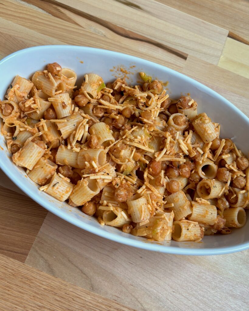 Oval bowl filled with Paprika Parmesan Rigatoni on a wooden table