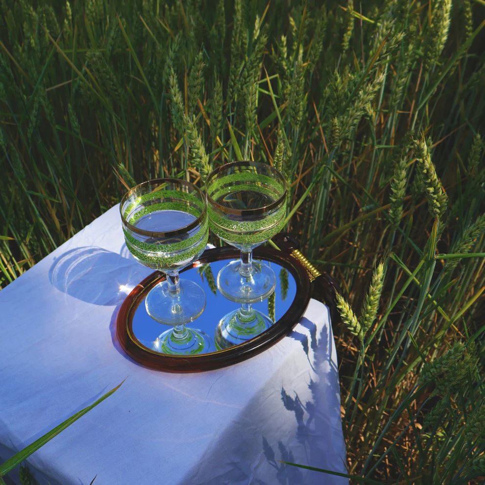 Two cocktails sitting on a little table in a field of grain