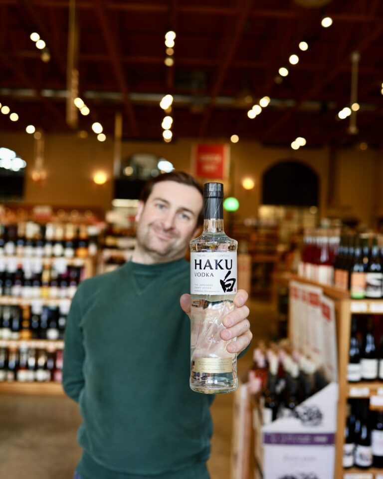 Matt holding a bottle of Haku Vodka in the liquor store