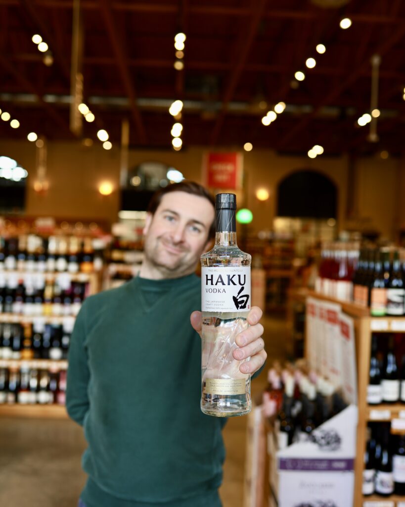 Matt holding a bottle of Haku Vodka in the liquor store