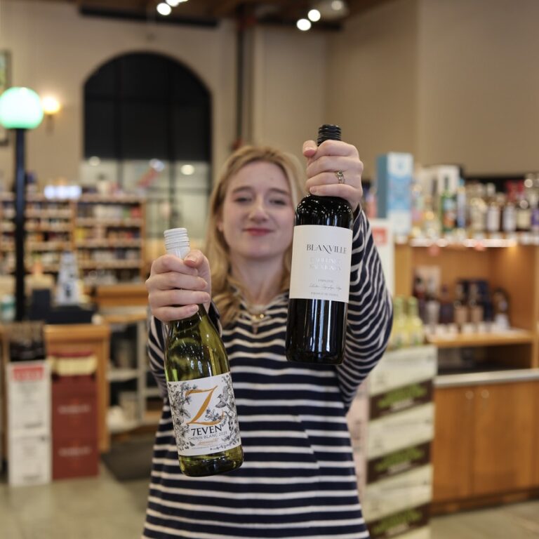 Audrey holding 2 bottles of wine in the Liquor Store
