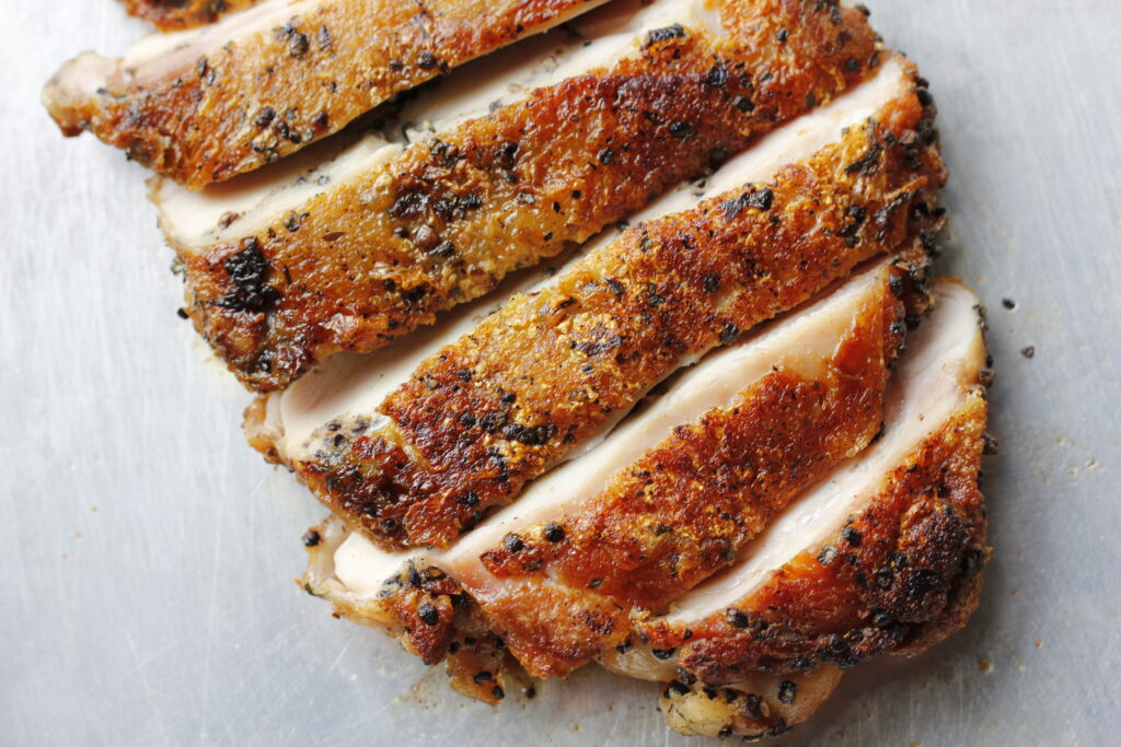 Cardamom chicken breast sliced on a sheet pan
