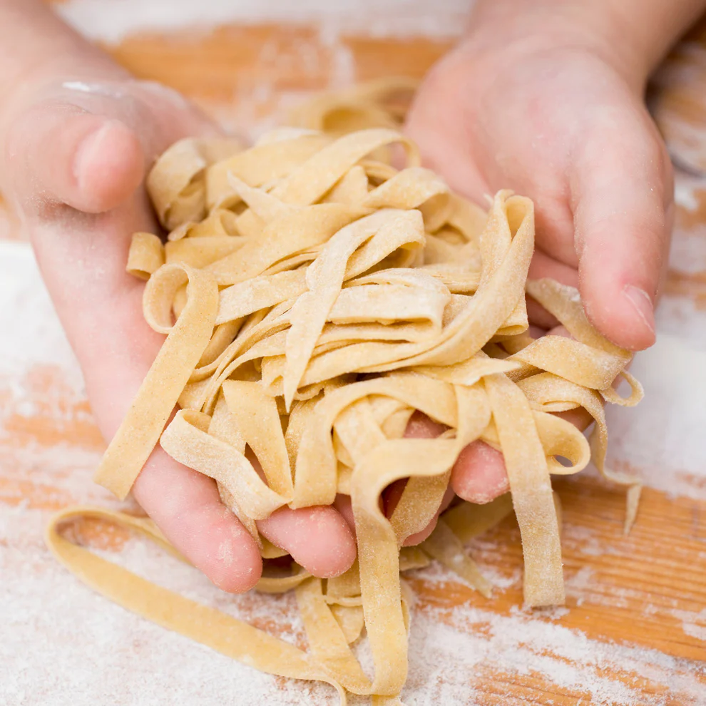 Hands holding a bundle of fresh pasta
