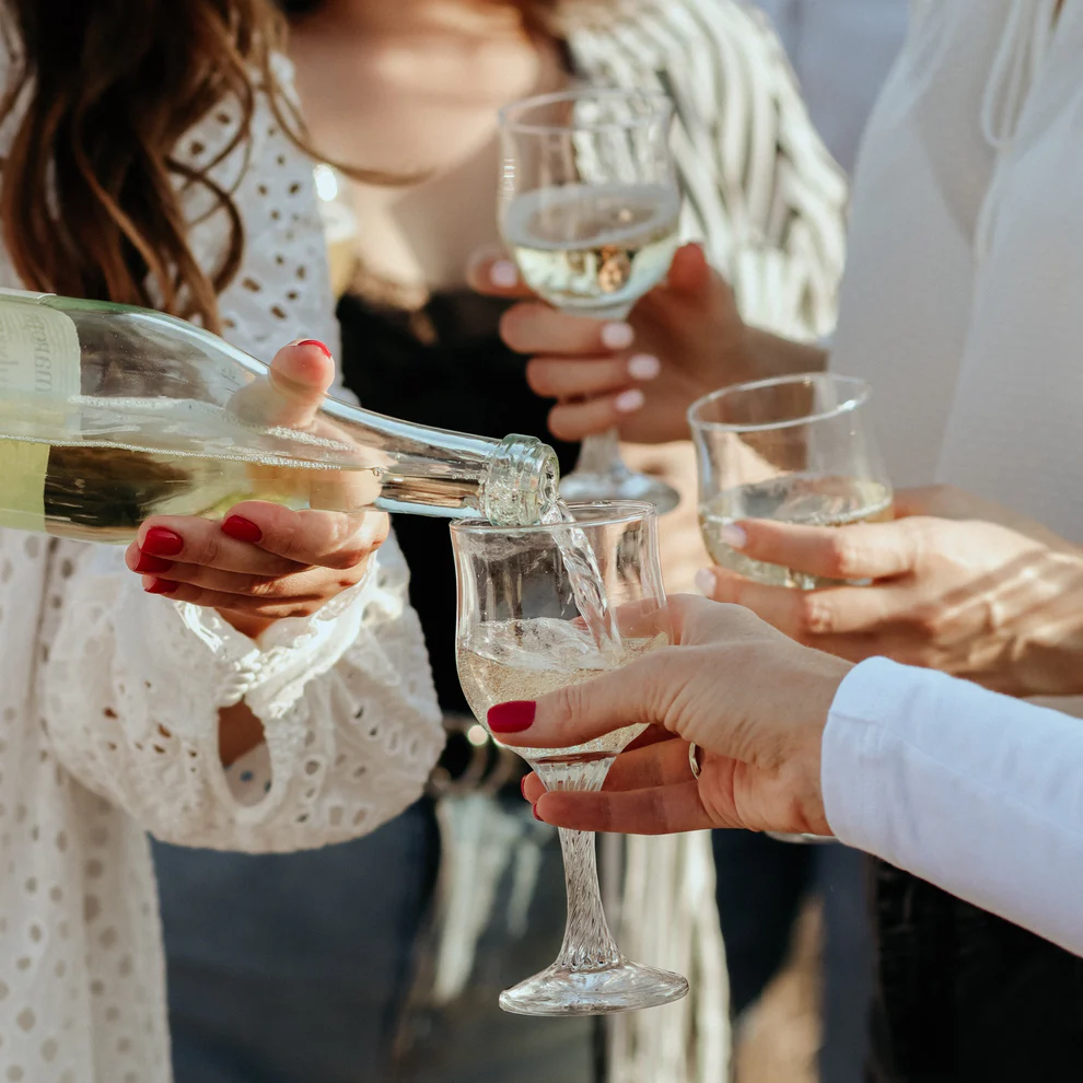 People pouring white wine outside
