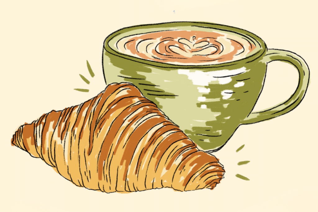 Latte in a green mug next to a croissant