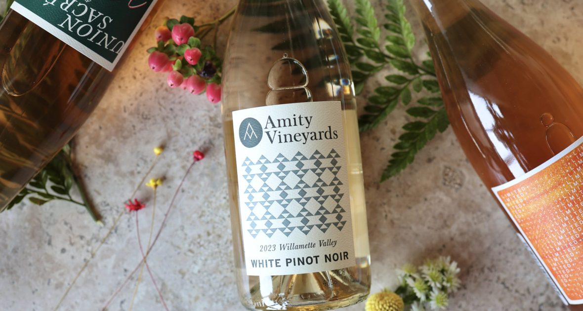 3 bottles of wine on a table with greenery and flowers