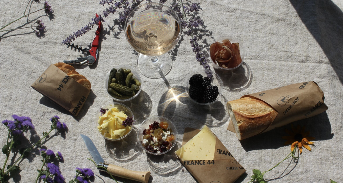 Birdeye view of picnic with baguette, cheese, drink